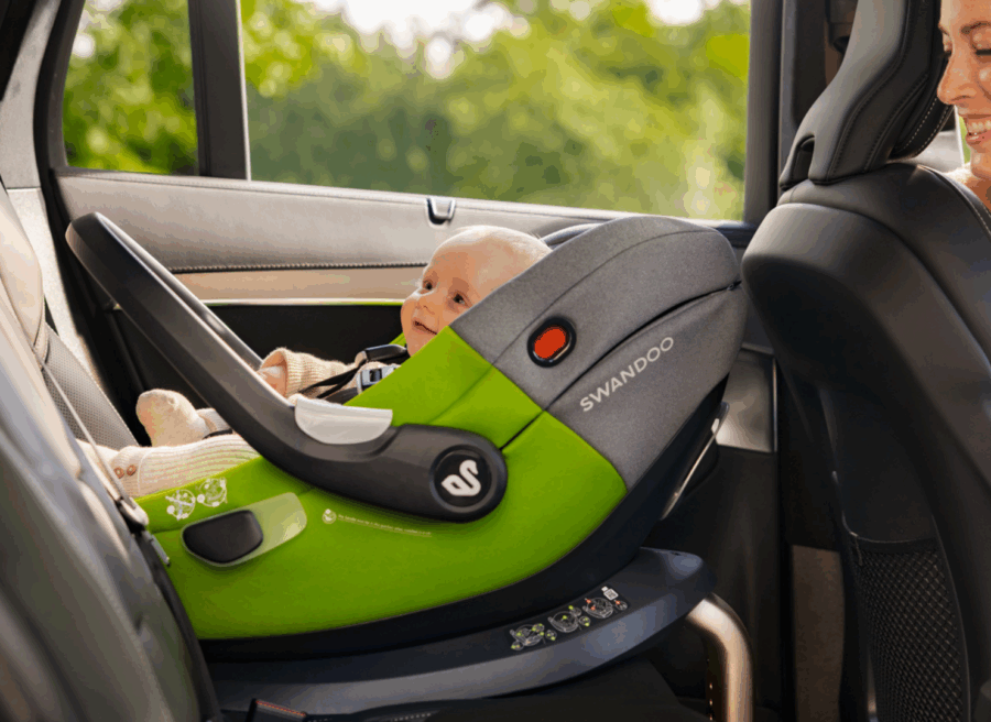 Mother looking at baby in Swandoo Albert i-Size baby car seat installed in car