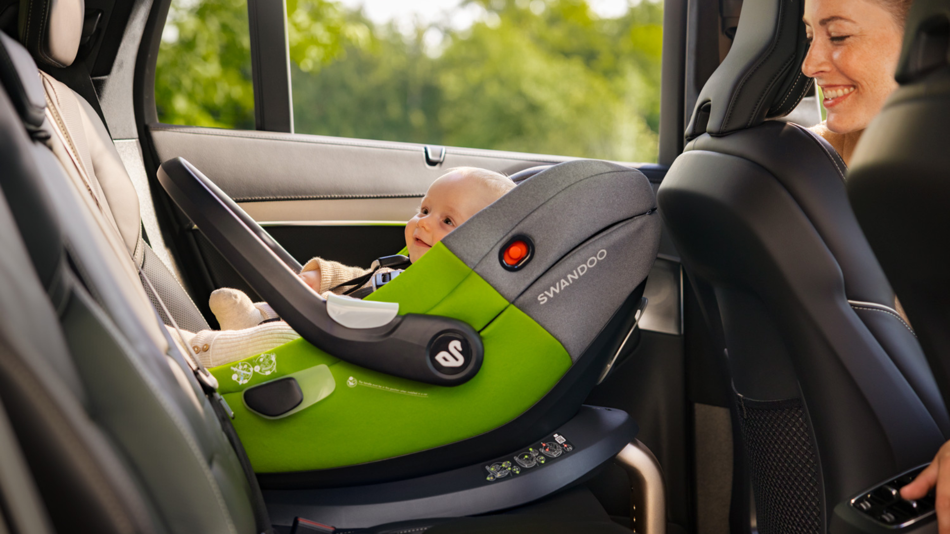 Mother looking at baby in Swandoo Albert i-Size baby car seat installed in car