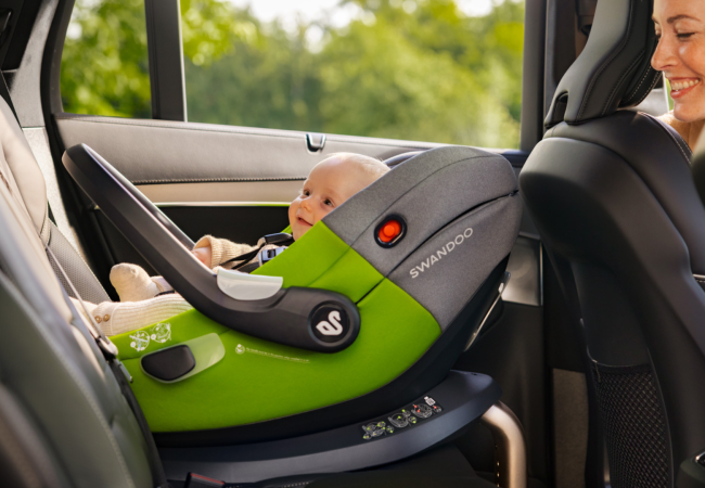 Mother looking at baby in Swandoo Albert i-Size baby car seat installed in car